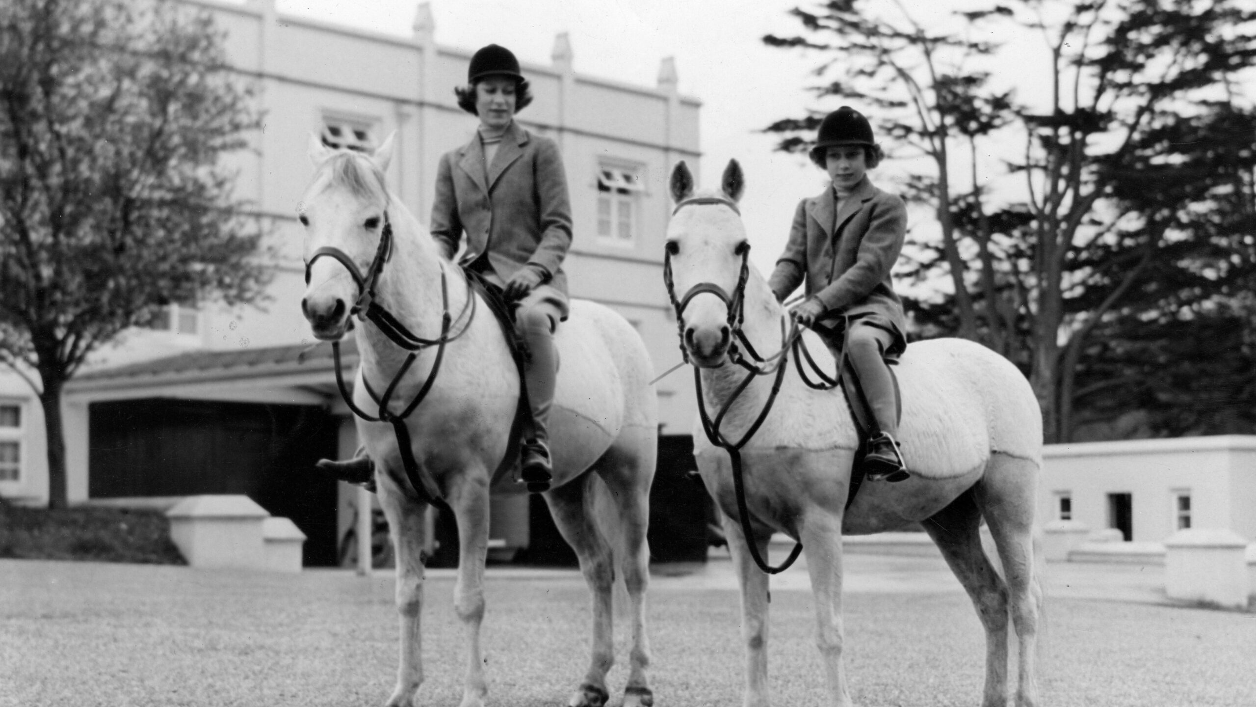 Princess Elizabeth (Queen Elizabeth II) and Margaret on horseback in the ground of Royal Lodge, Windsor c. 1940.