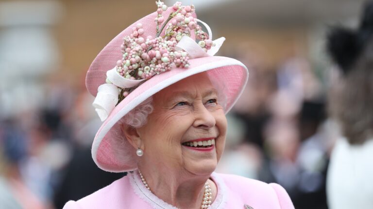 Queen Elizabeth II wearing pink and smiling.