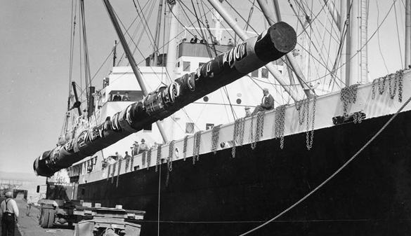 The totem pole being lowered onto a vehicle from a docked ship.