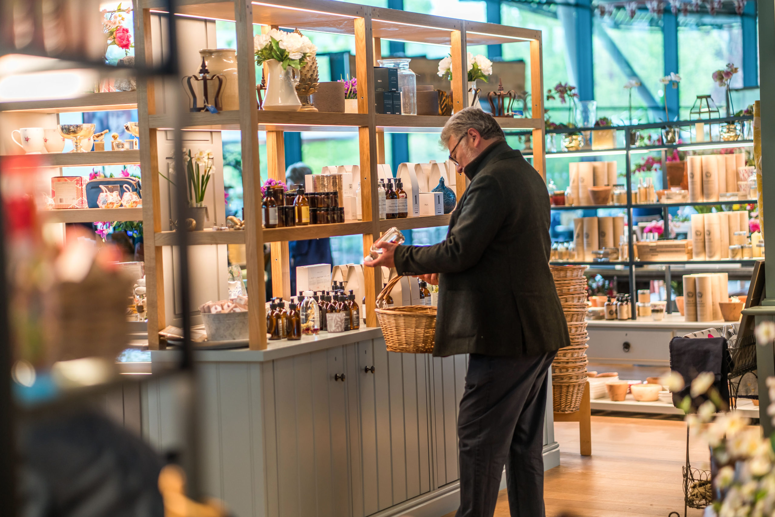 Adult reaching for a product from a shelf at The Savill Garden Gift Shop.
