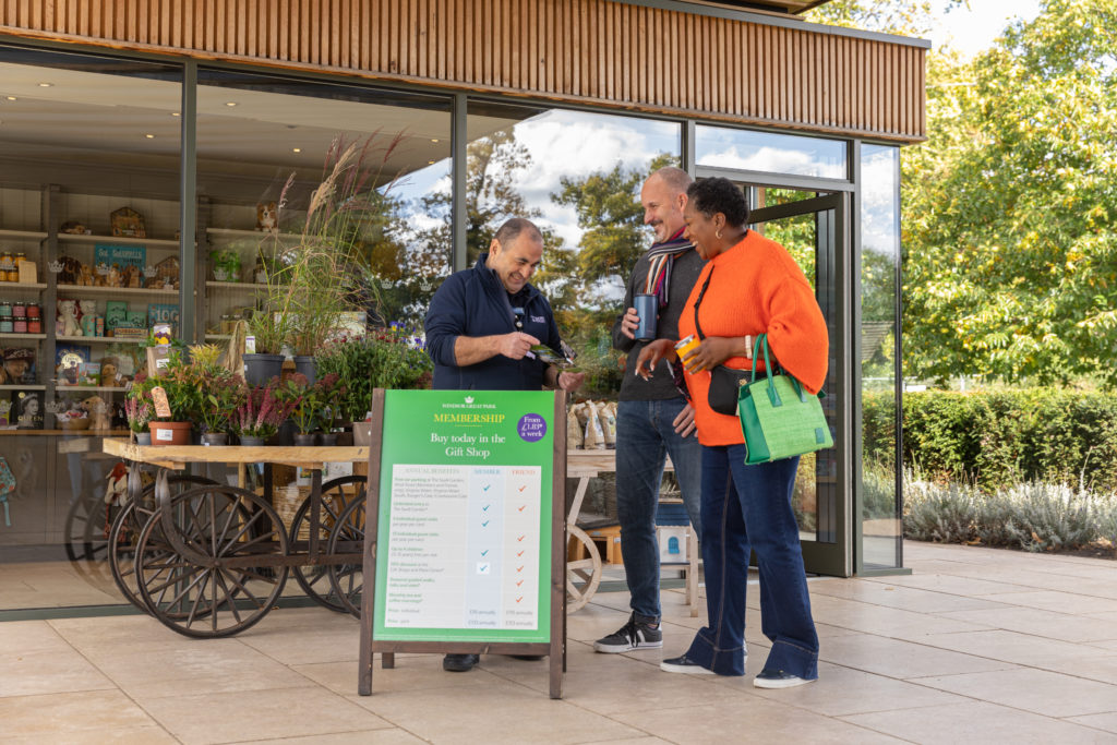 Two people speaking with a member of staff outside Virginia Water gift shop