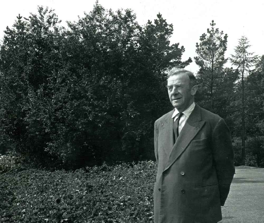 Eric Savill stands amongst the trees and shrubbery of The Savill Garden.