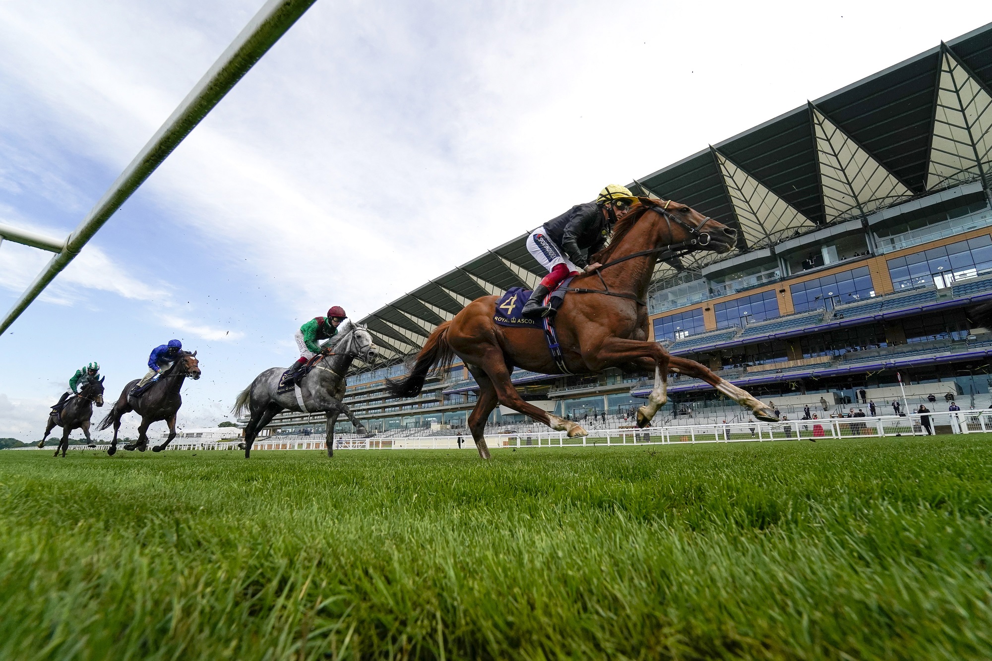 Four horse riders on horseback racing at Ascot race course.