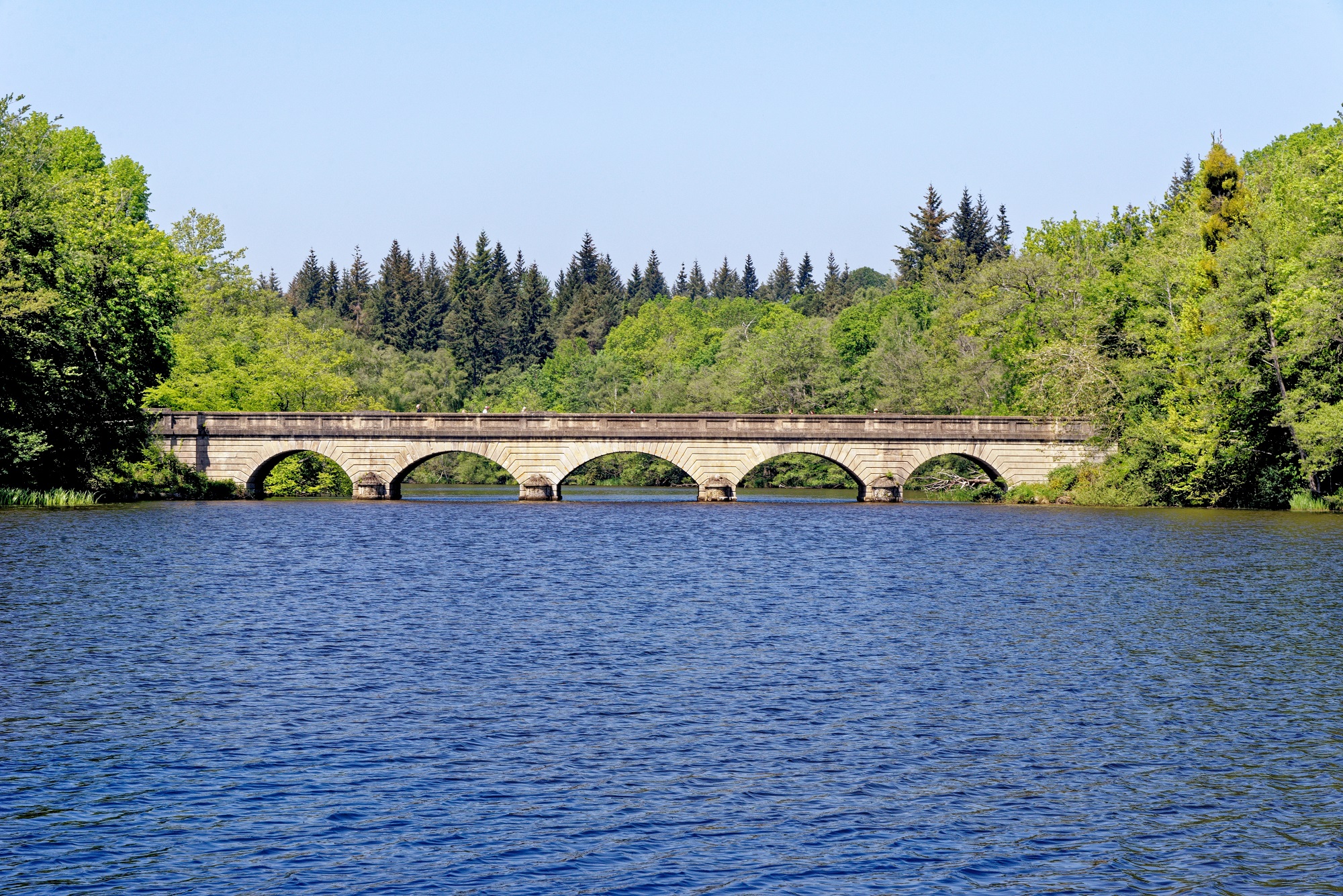 Five Arch Bridge at Virginia Water Lake with trees in the background.