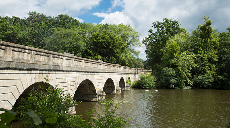 Five Arch Bridge at Virginia Water Lake with trees in the background.