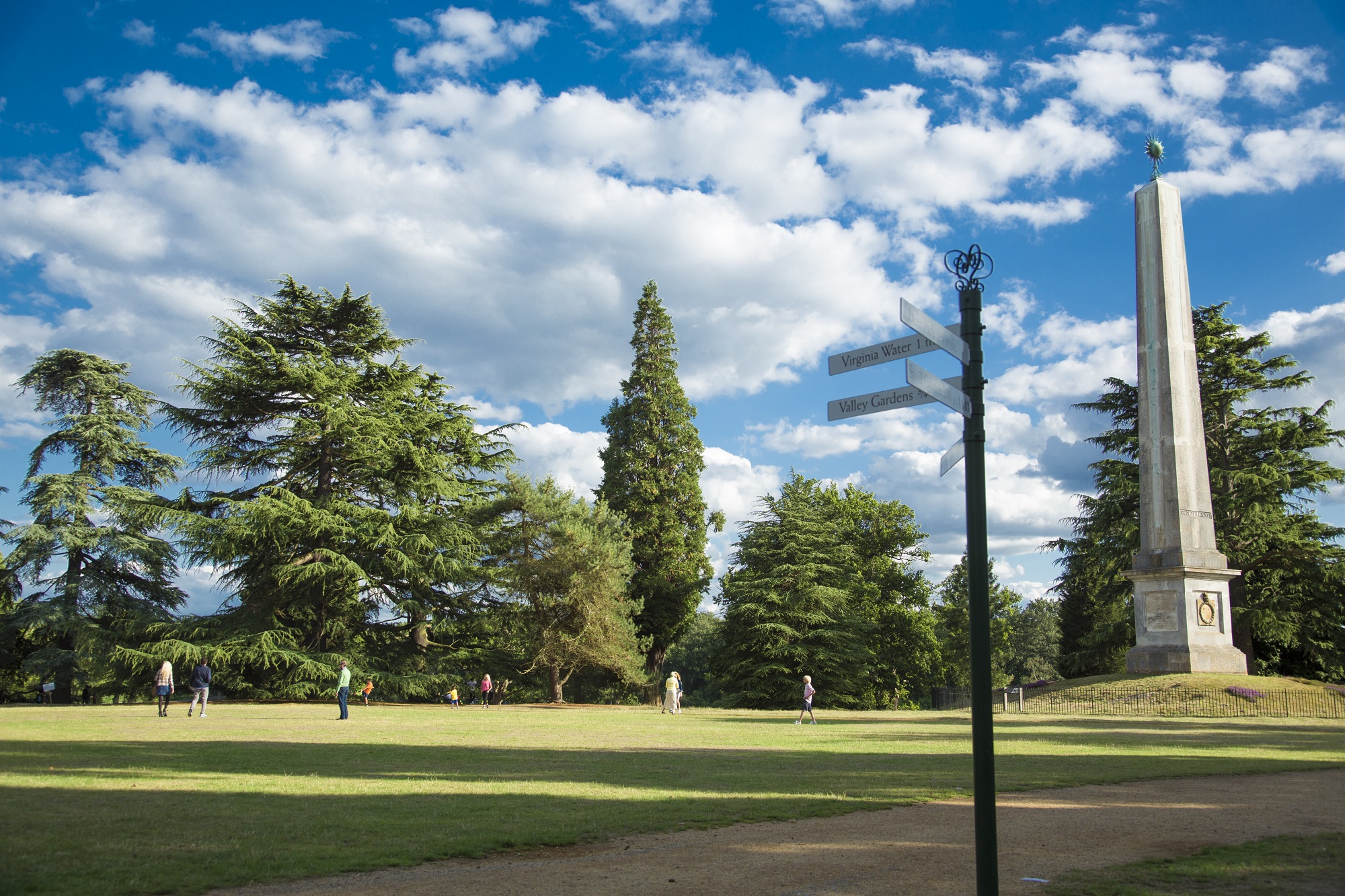 Obelisk Lawn and Pond with people on the Lawn and trees in the background.