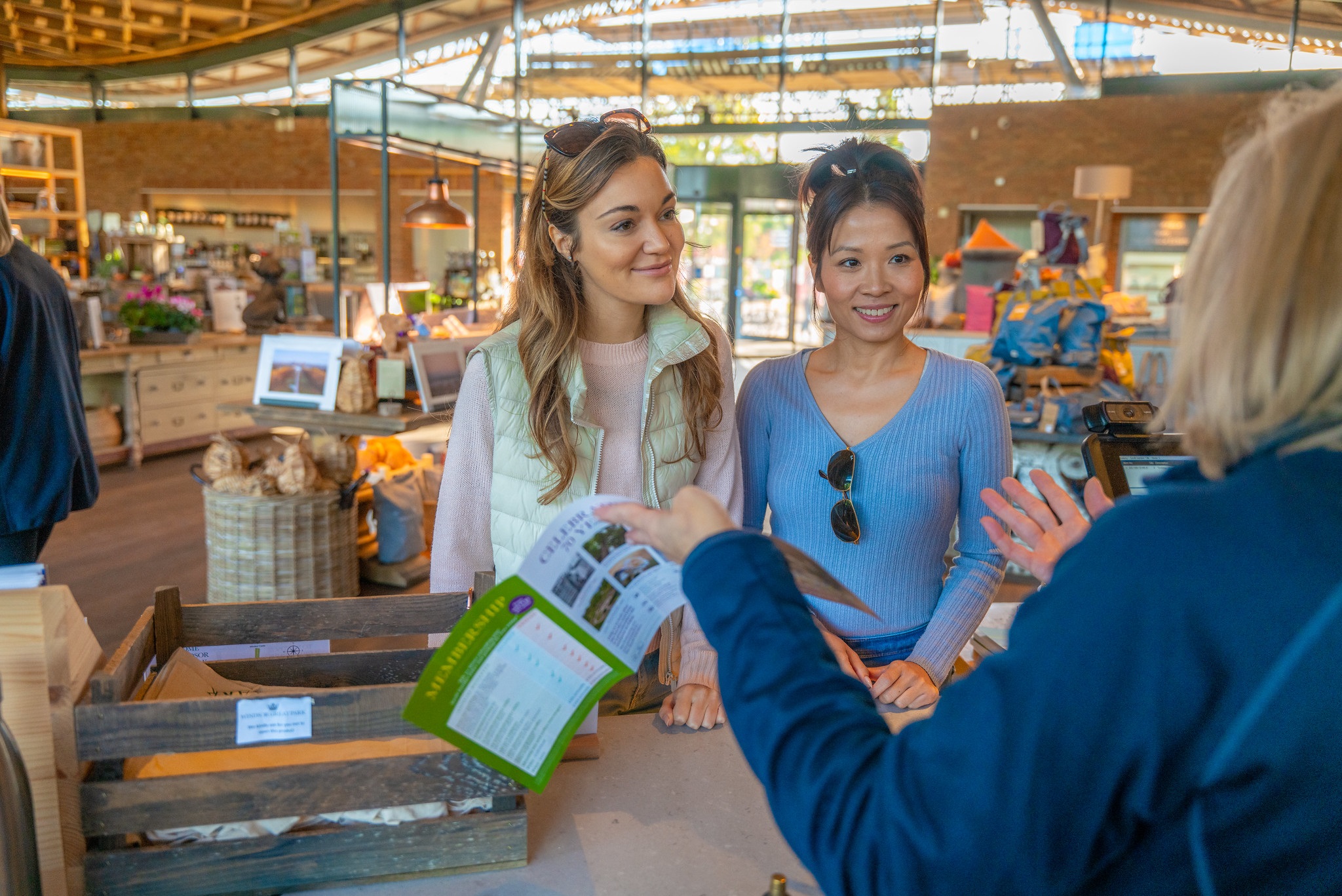 Two adults speaking to a staff member in The Savill Garden Visitor Centre.