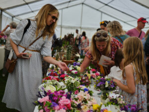 Adults and children in a marquee looking at flowers.