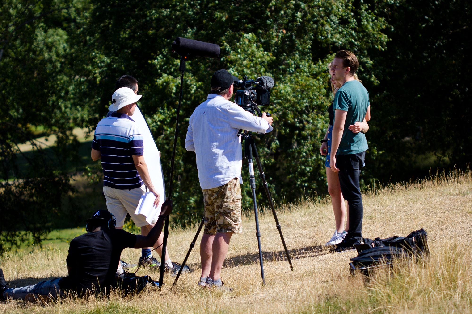 Young couple being filmed in a park with three film and camera crew.
