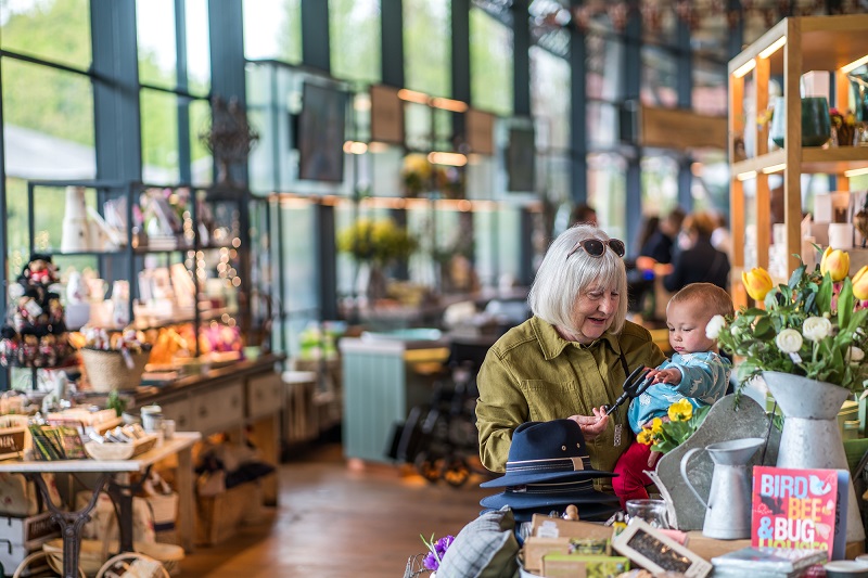 Adult holding a baby in the Savill Garden shop.