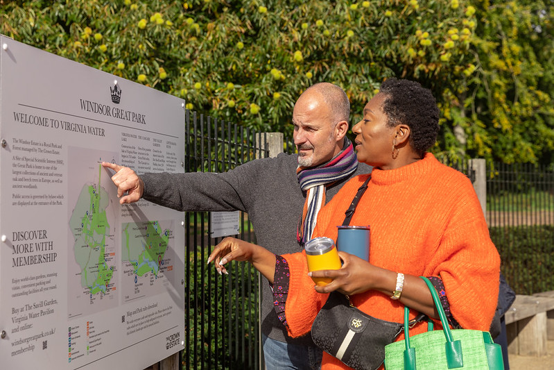 Couple looking at an entrance sign at Virginia Water Lake. 