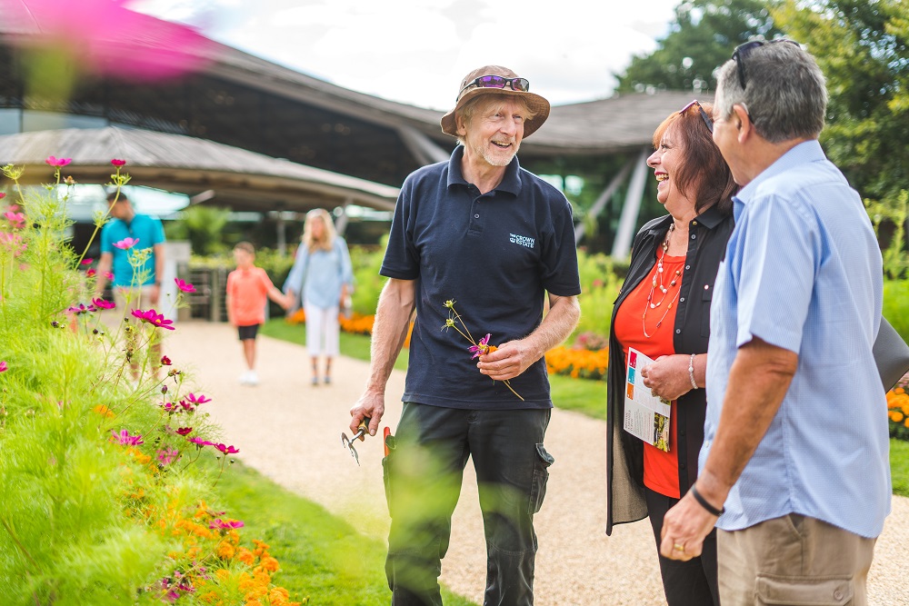 Gardener talking to two adults with a family in the background at The Savill Garden.