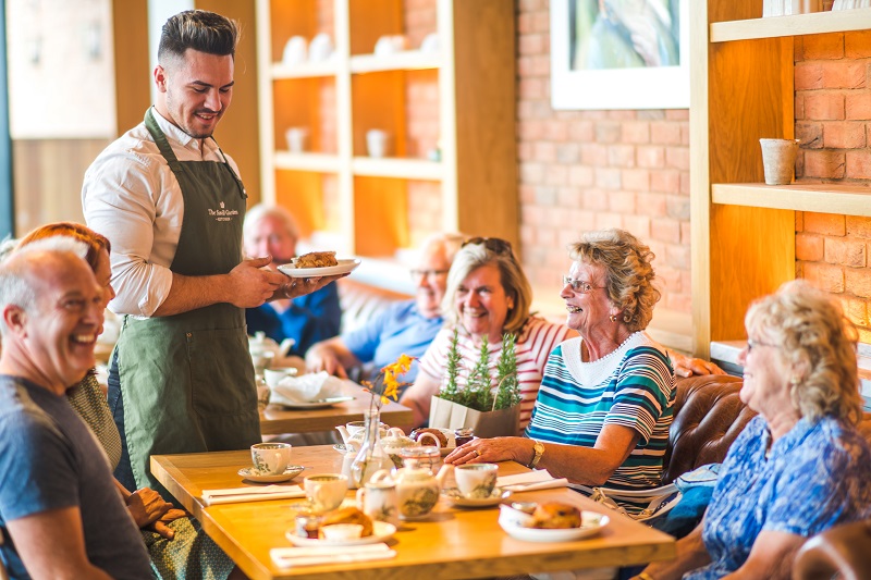 Group of customers being served a cream tea in The Savill Garden Kitchen. 