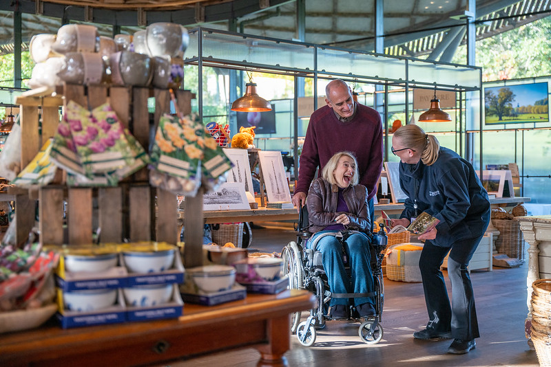 Two adults, one standing and one wheelchair user, talking to a member of staff.