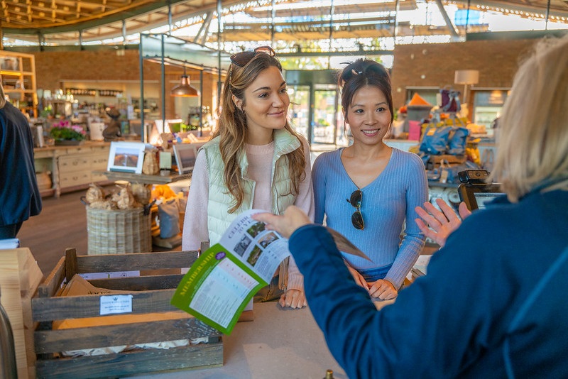 Two adults speaking to a staff member in The Savill Garden Visitor Centre.