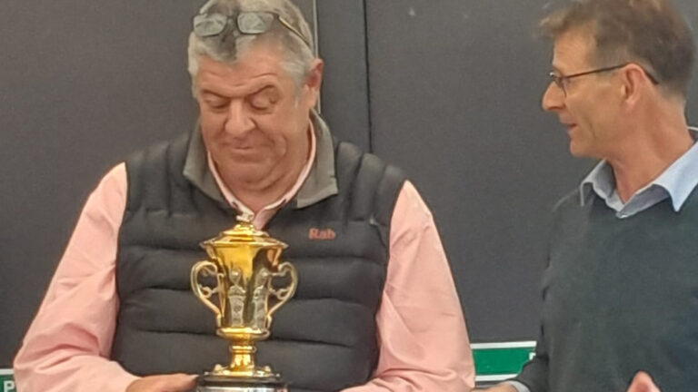 John Anderson, Keeper of the Gardens, wearing a black gilet and cream shirt holding a gold trophy.