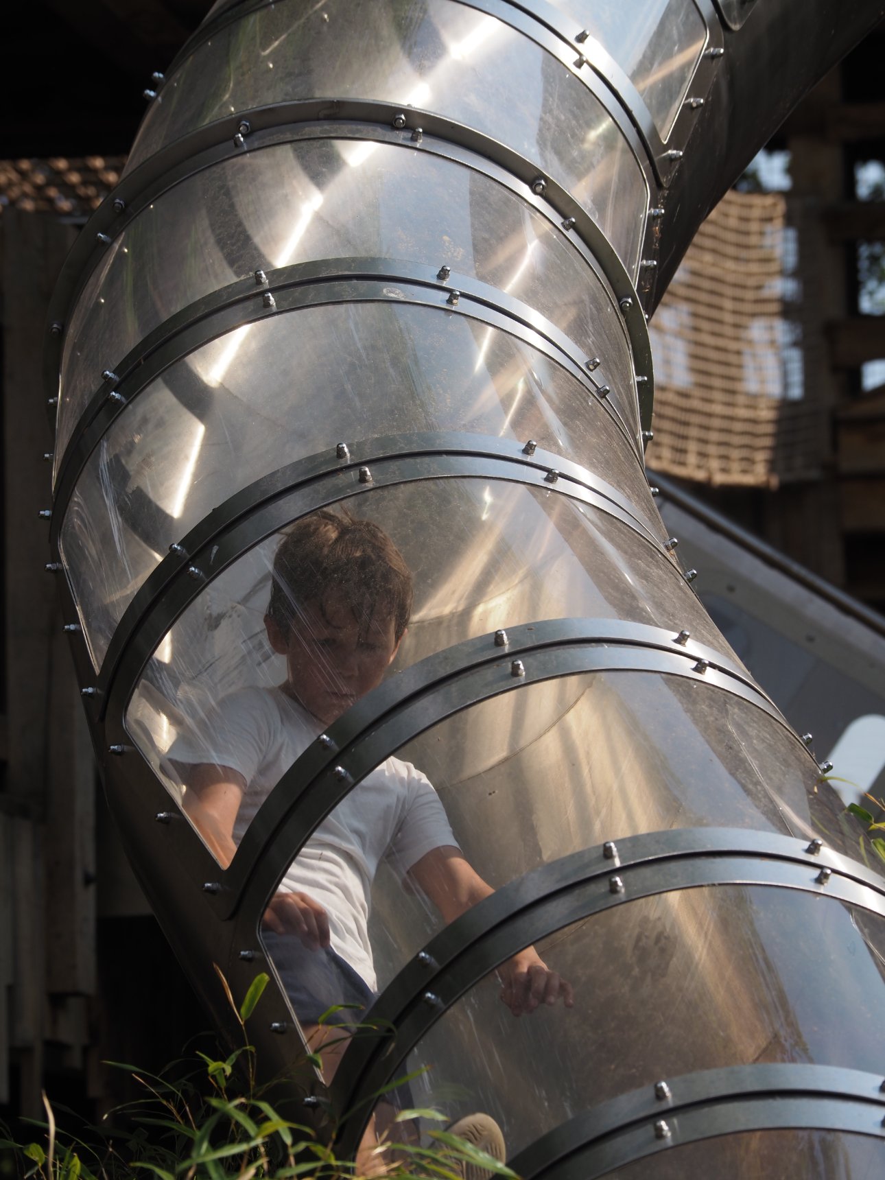 Young child sliding down a Perspex covered slide.