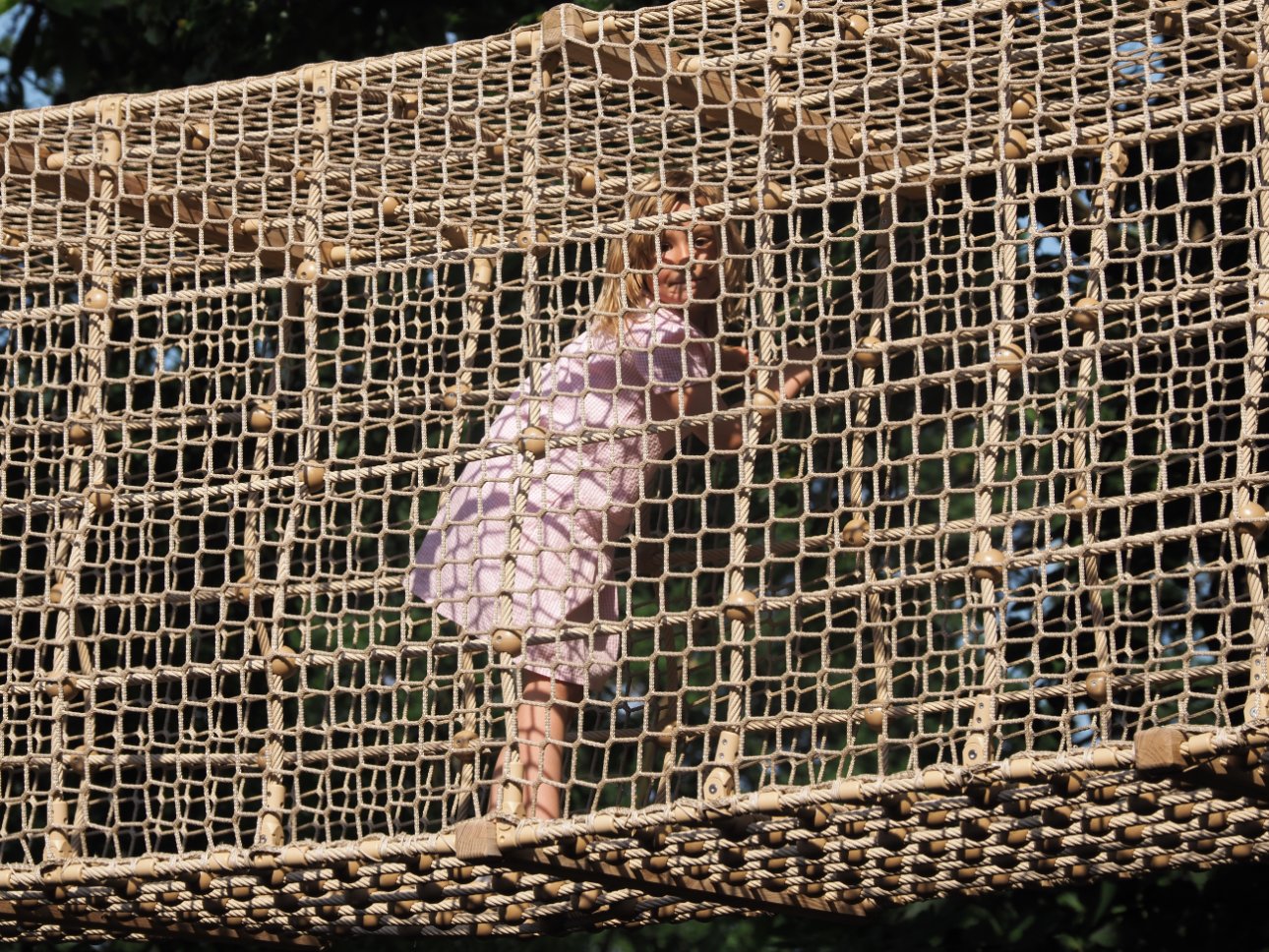Young child climbing through a net frame.