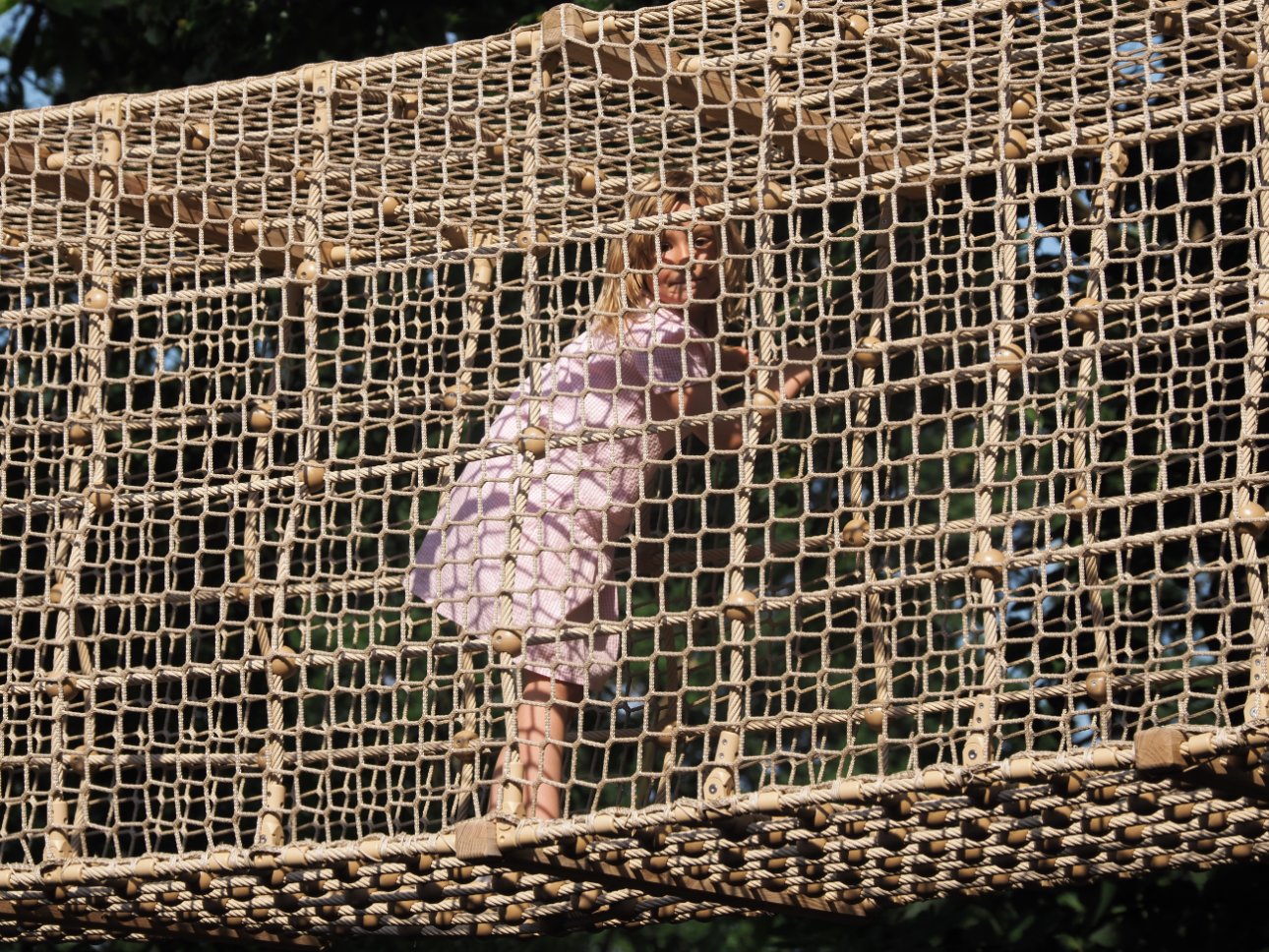 Young child climbing through a net frame.