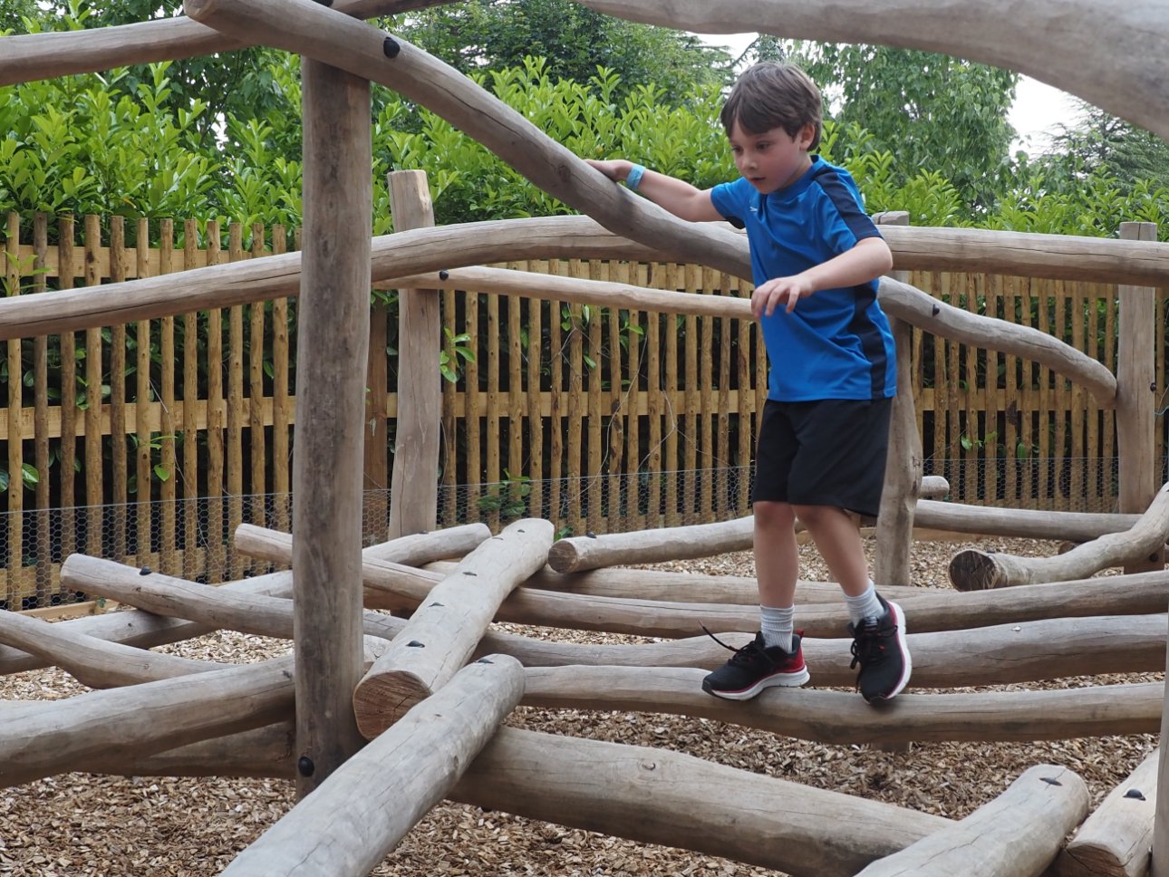 Young child climbing across logs.