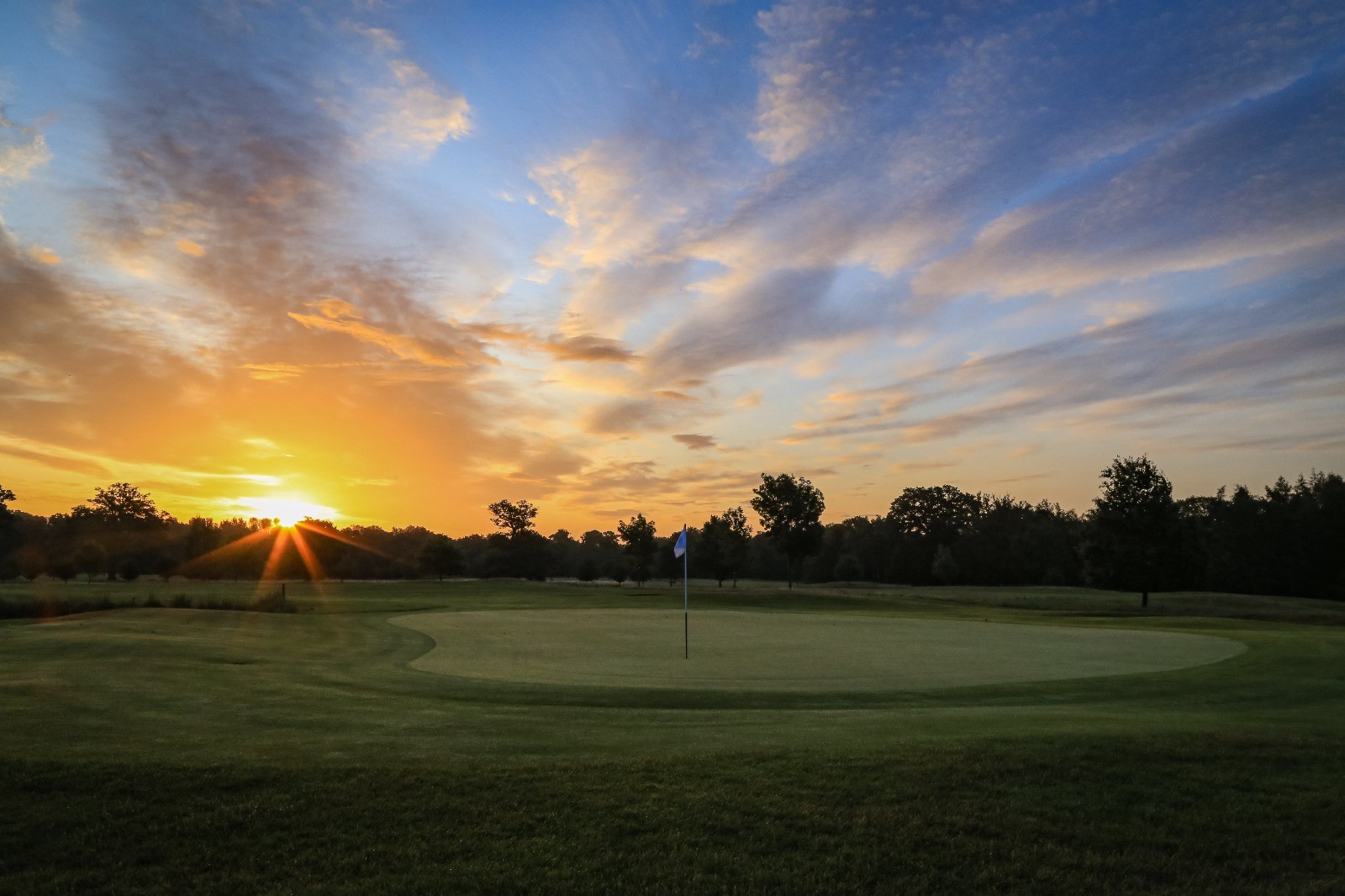 A golf tee with the sun rising in the background.