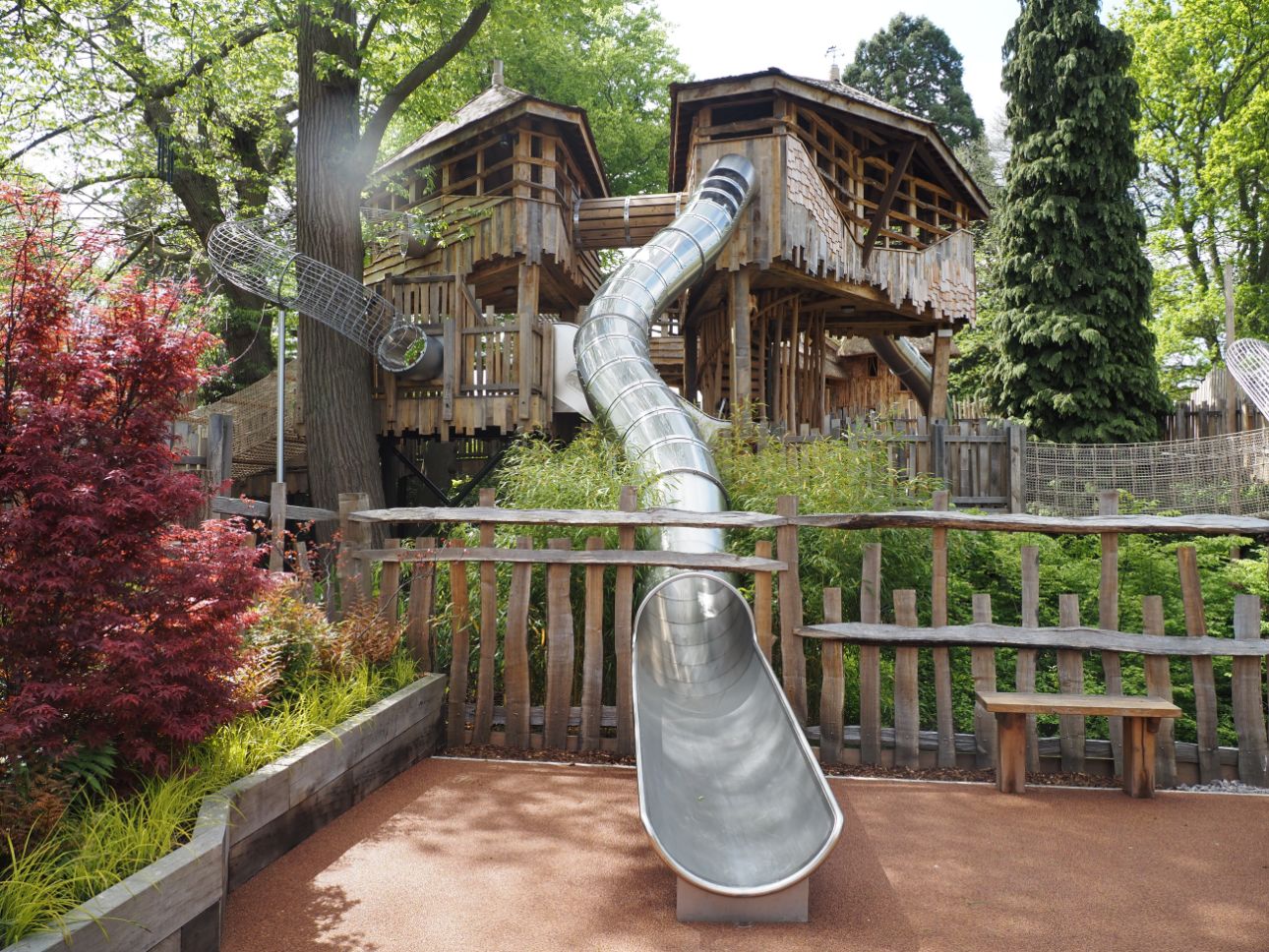 Treehouses and slides surrounded by trees and green vegetation.