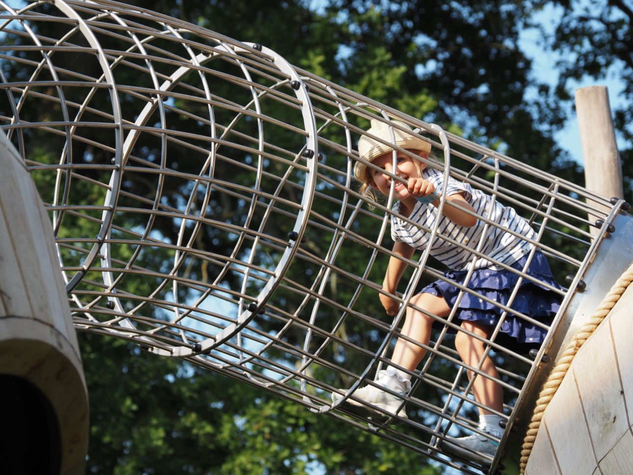 Young person climbing through metal crawl tunnel.