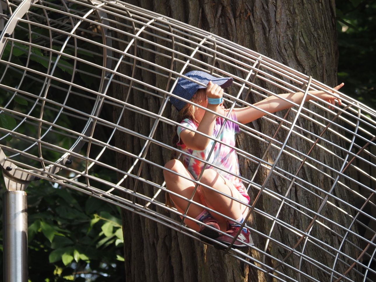 Young child climbing through a metal frame.