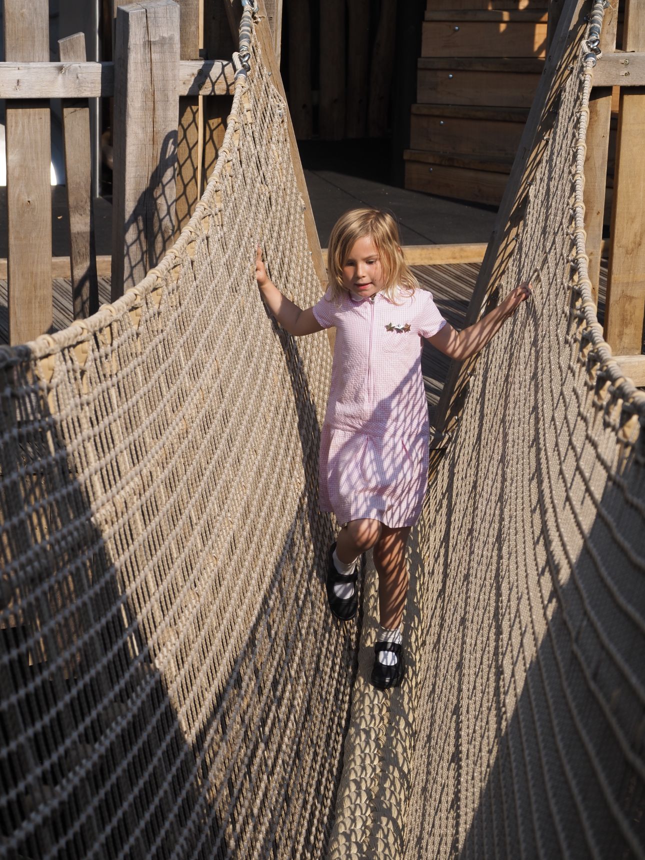 Young child walking across a net bridge.