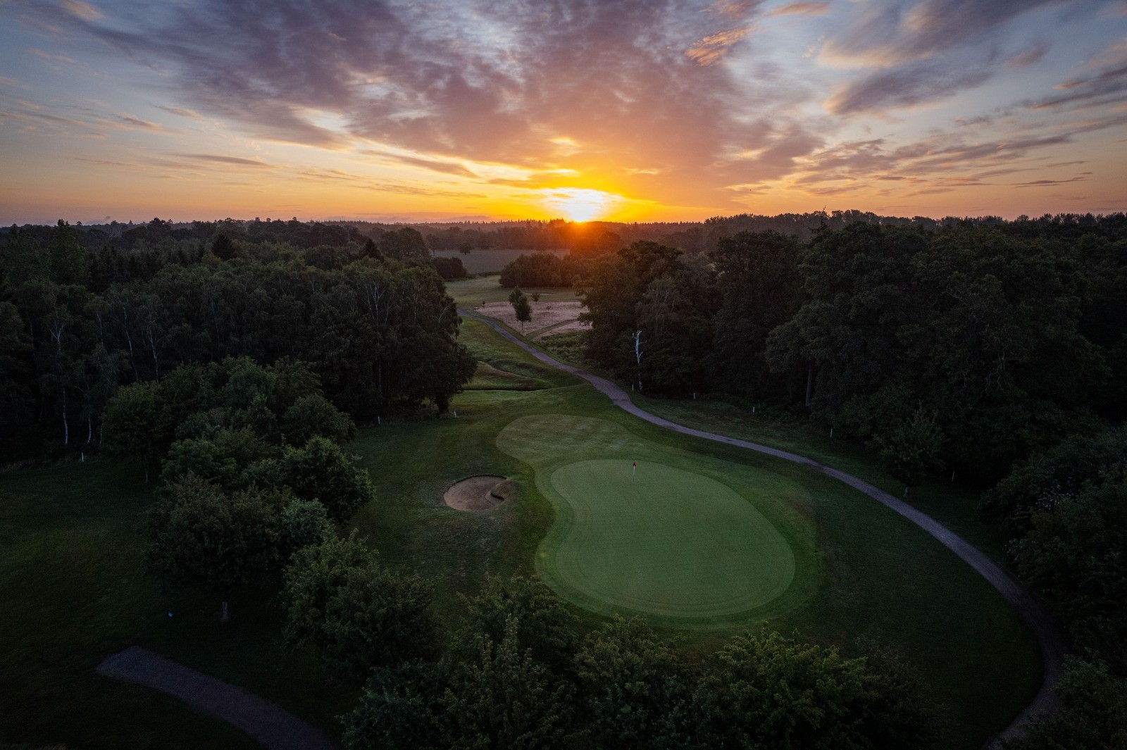 Aerial view of The Royal Ascot Golf Club with the sun rising in the background.