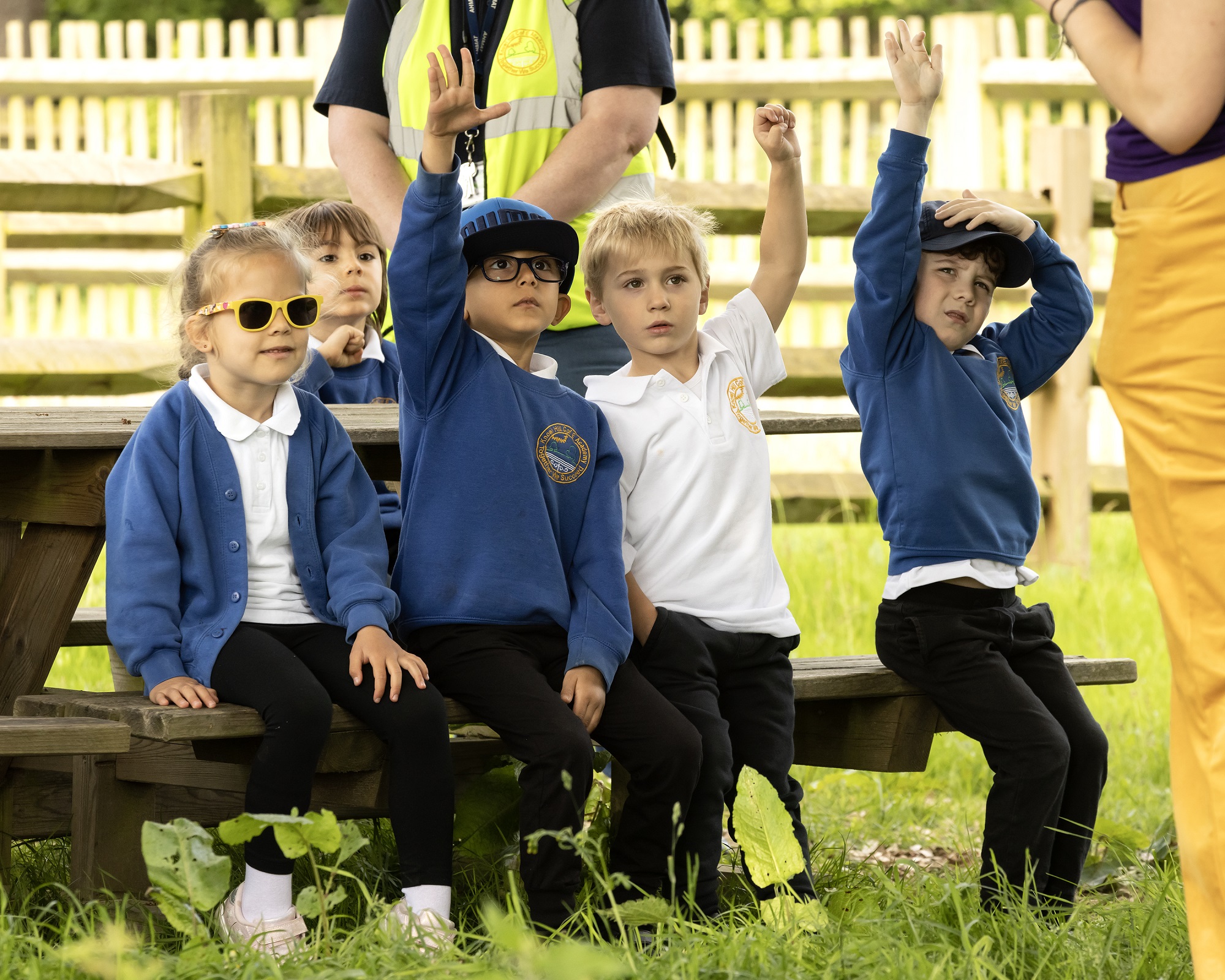 Group of young children raising their hand to answer a question.. 