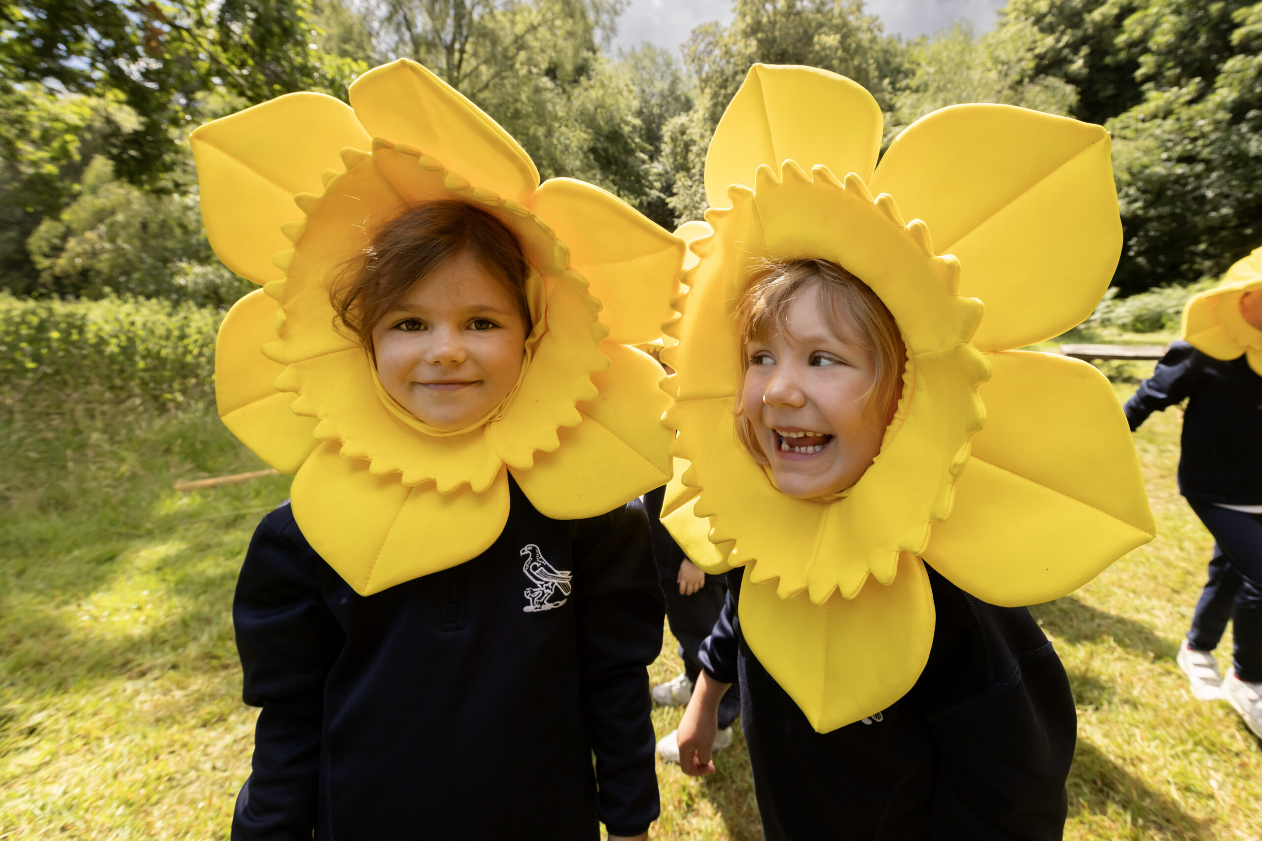 Two young children wearing a bright yellow daffodil head dress.