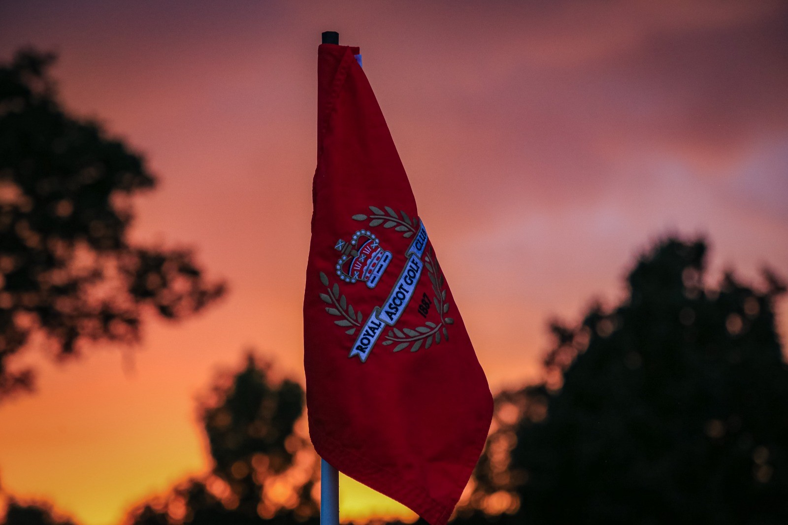 A red flag with the Royal Ascot Golf Club logo.
