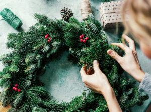 A picture of someone making a Christmas wreath, their hands and the back of their head are in shot as they look down at their work.