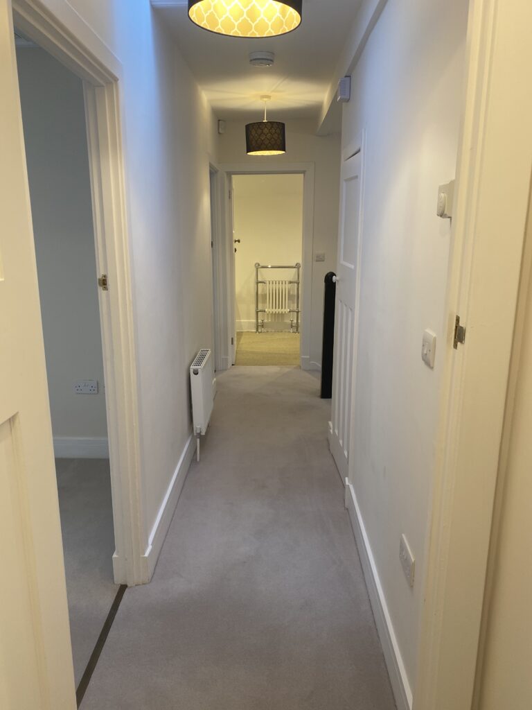 A carpeted and white walled hallway in Pinewood Lodge, Swinley Road, Ascot, SL5 8BA