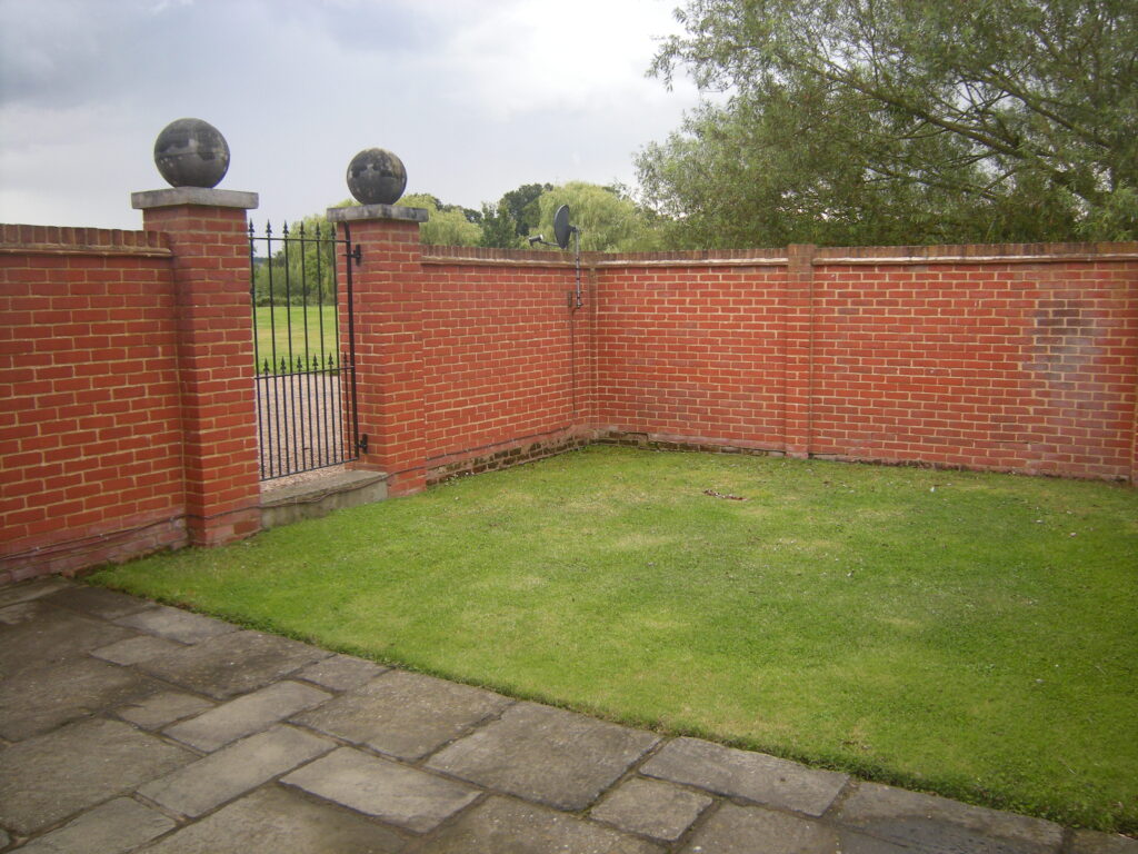 A view of the side garden lawn and gate in 6 Home Farm, Bagshot Park