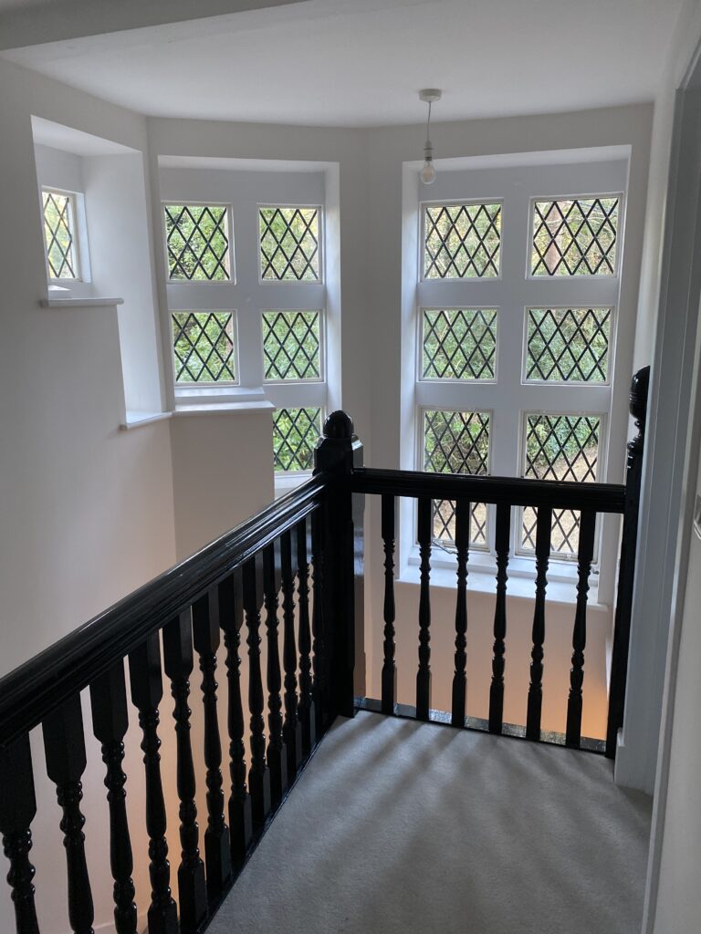 A carpeted and white walled landing with wooden banister in Pinewood Lodge, Swinley Road, Ascot, SL5 8BA