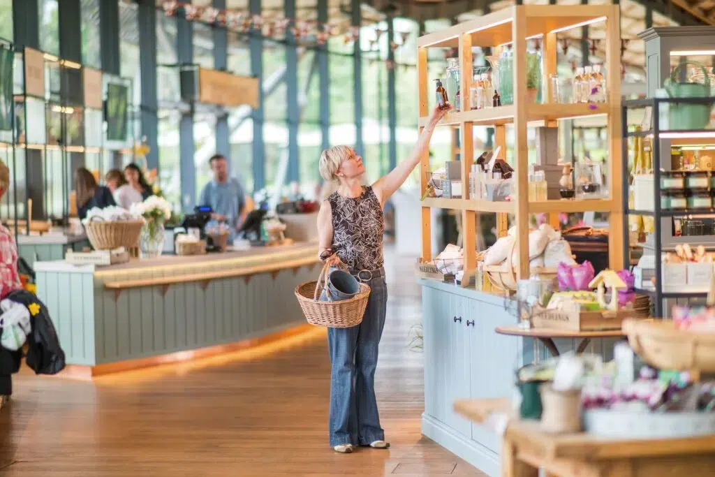 Adult reaching for a product from a shelf at The Savill Garden Gift Shop.