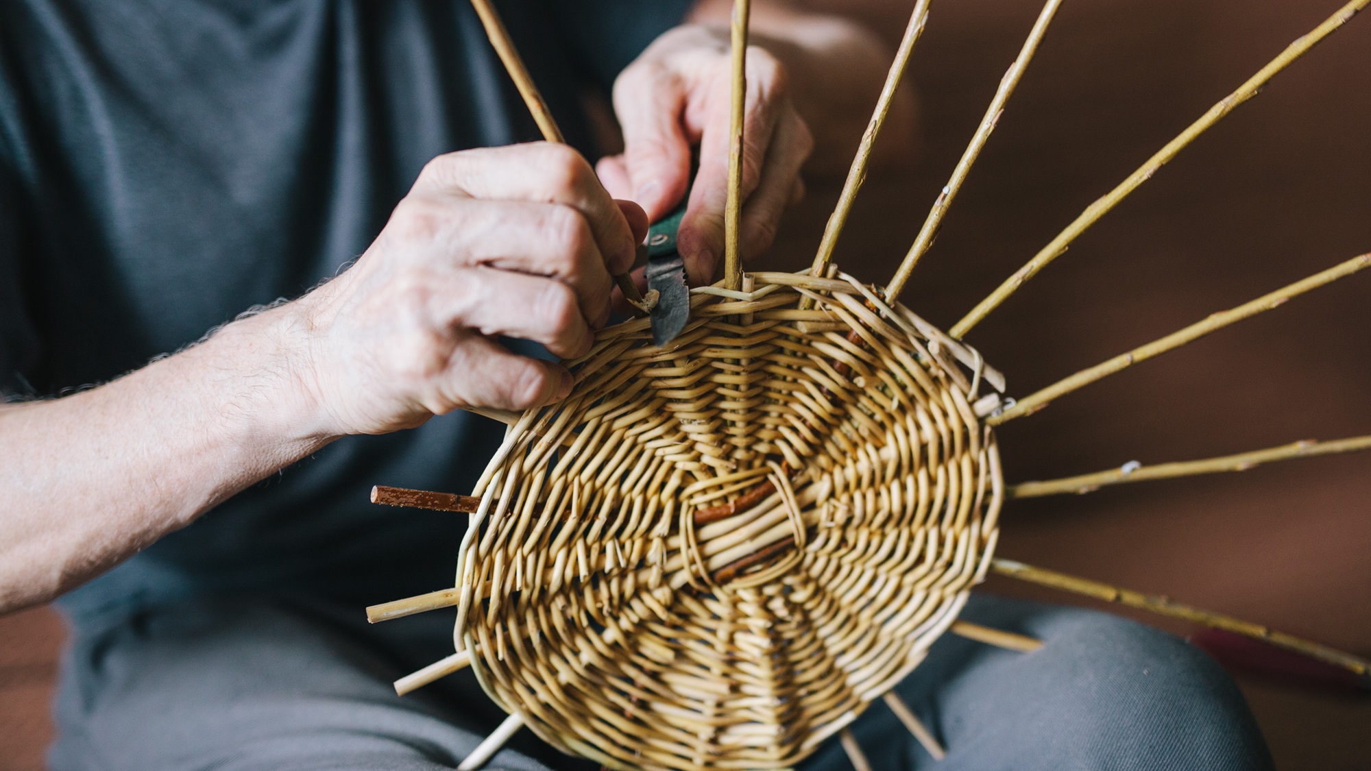Adults hands weaving a basket.