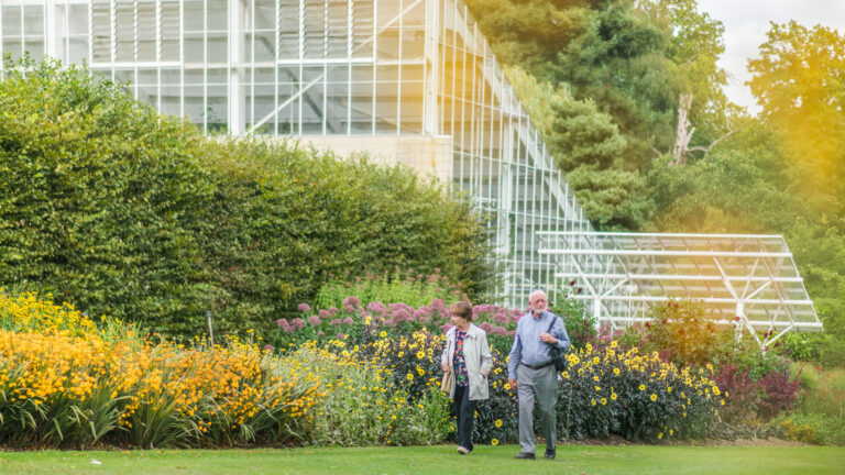 Two people walk beside the herbaceous border, with the Queen Elizabeth Temperate House behind.
