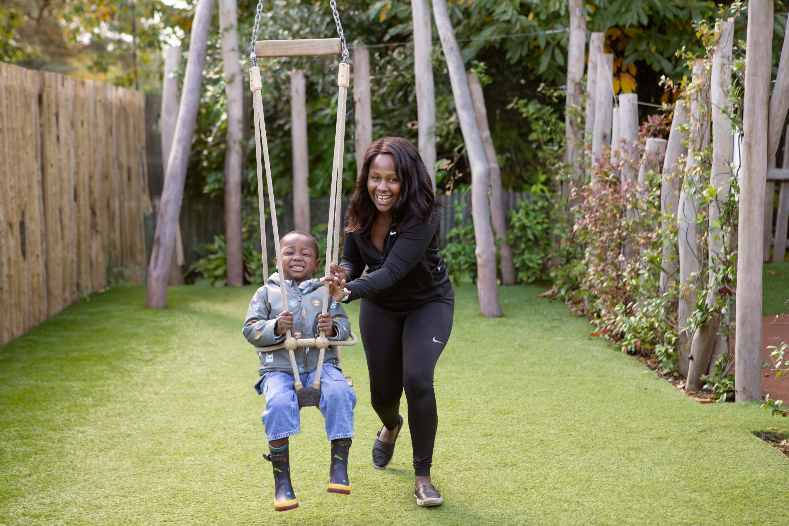 Young child in a suspended line swing. Eyes closed and supervised by an adult.