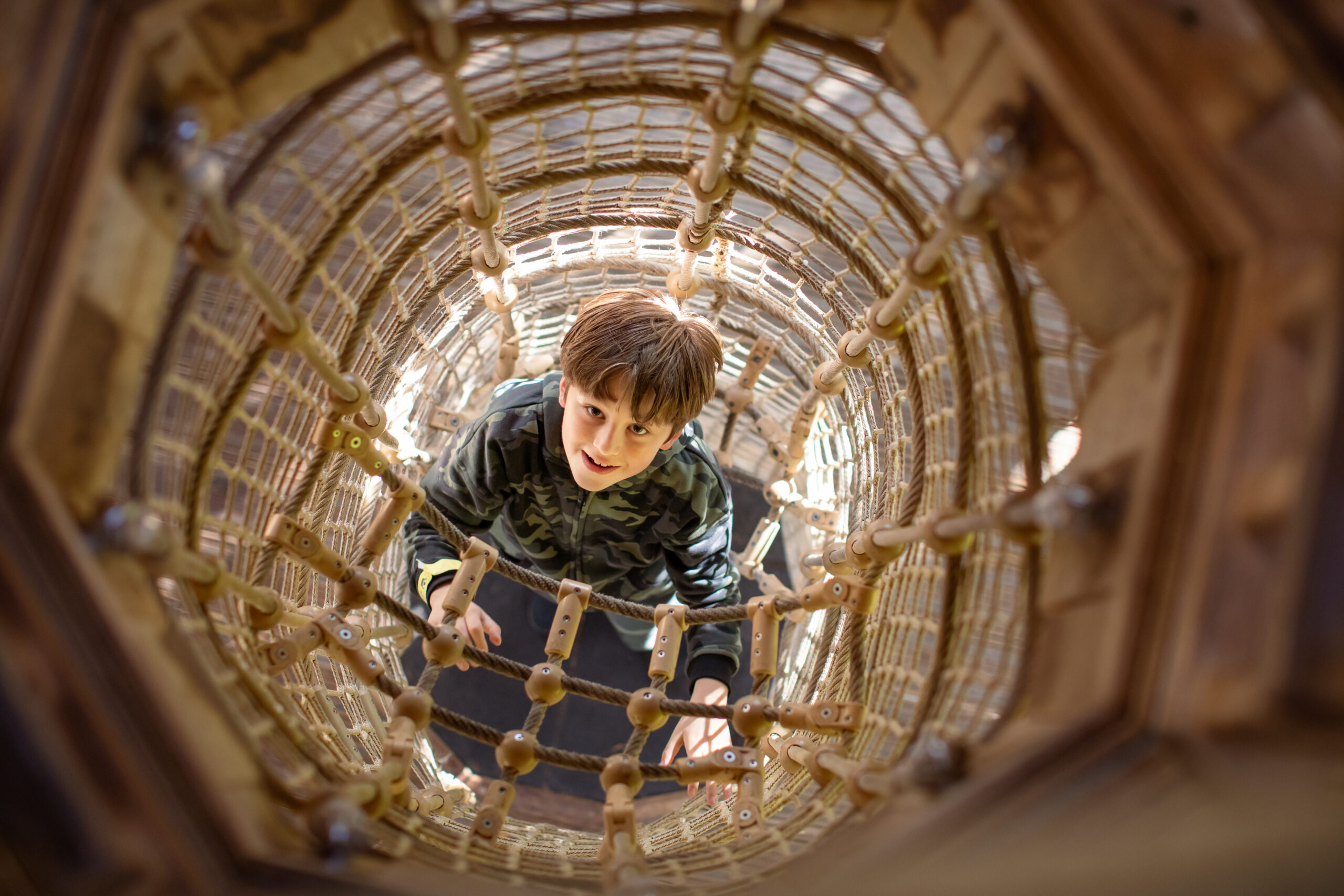Young child climbing through a rope net.