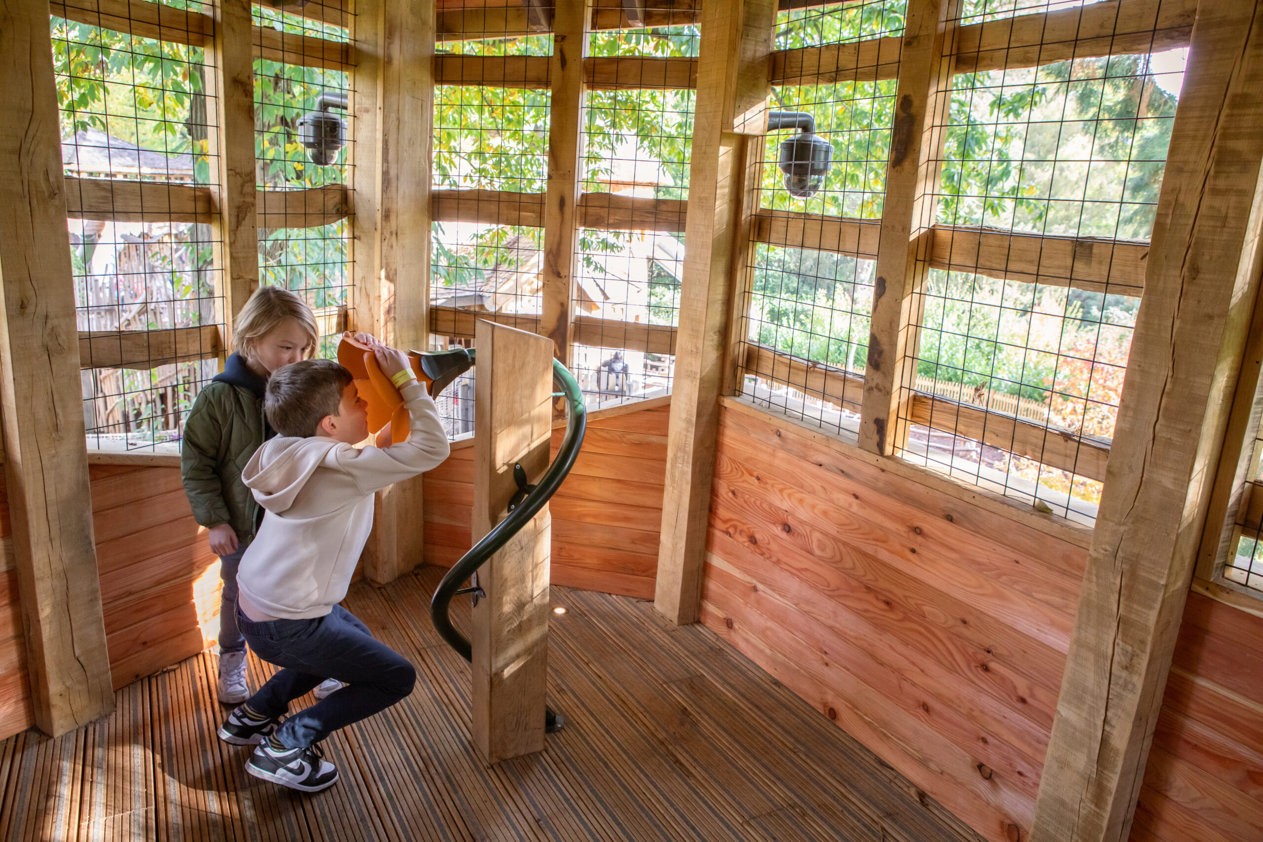 Two young children in a hut. One child is speaking in to a megaphone.