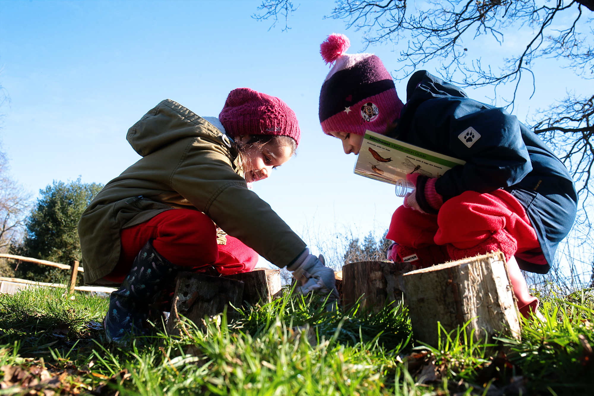 Two children looking for bugs in the grass.
