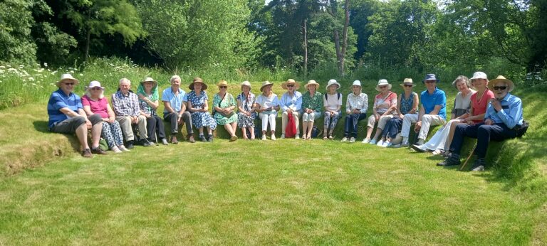 A group of people sitting in a semicircle on small hill.