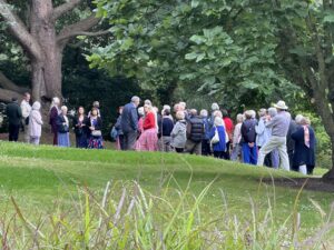 People on a guided walk in a Garden, with a green lawn in front of them.