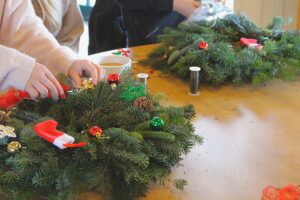 A child attaching baubles to a wreath.