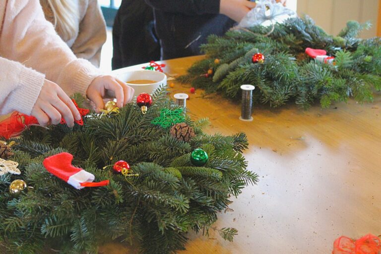 A child attaching baubles to a wreath.