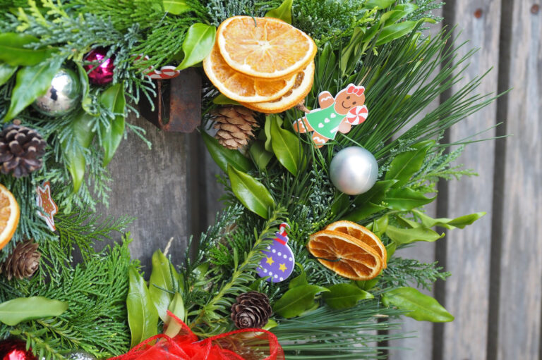 A close up of a Christmas wreath with leaves, pinecones and baubles.