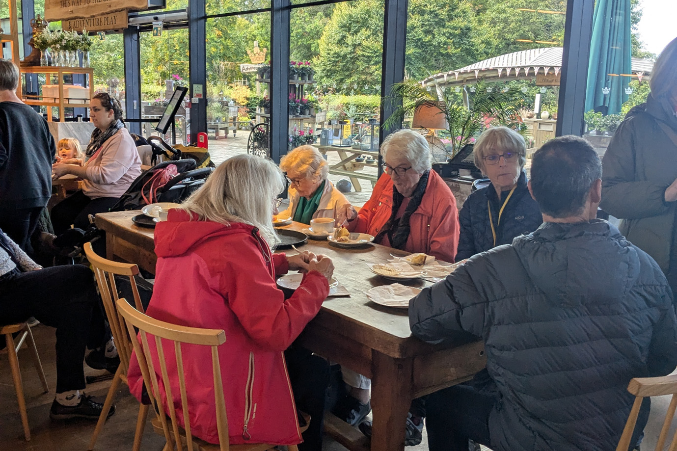 People seated at wooden tables eating cake.